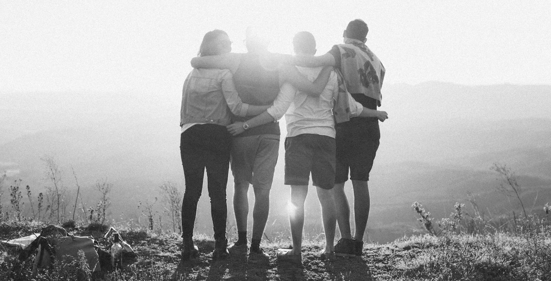 Four people standing together on a misty mountain, embracing each other.
